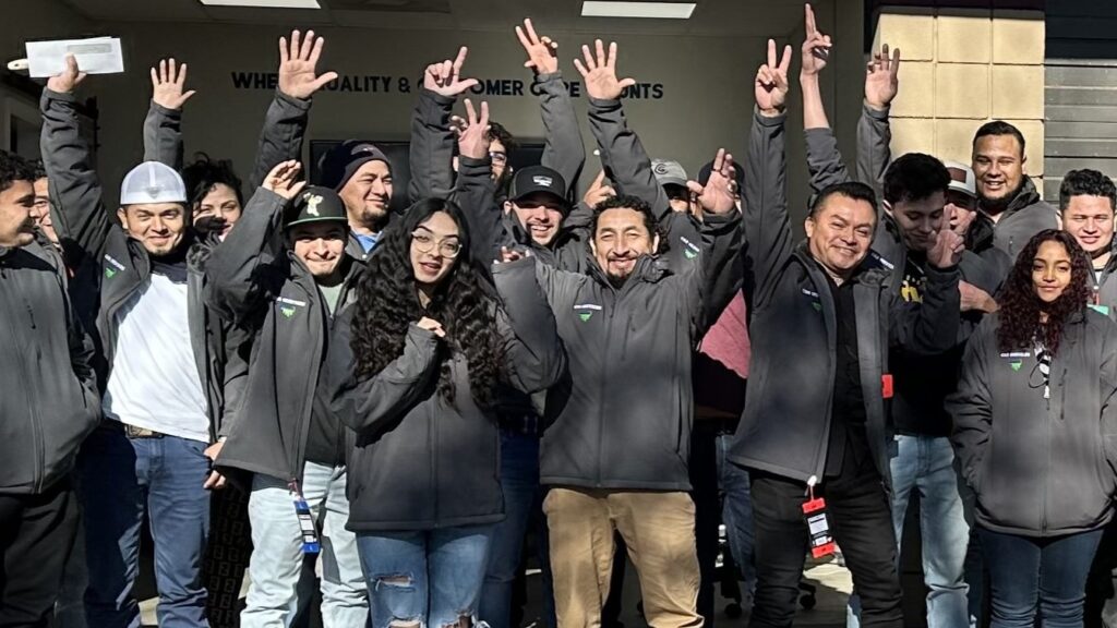 A large group of C&R Pro employees smiling and waving at the camera.