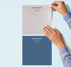 A close up of someone applying two Sherwin-Williams Peel-and-Stick Paint Swatches in shades of blue