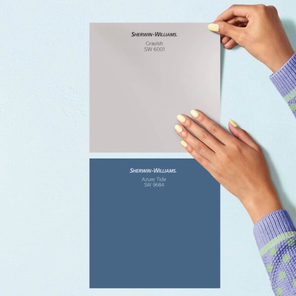 A close up of someone applying two Sherwin-Williams Peel-and-Stick Paint Swatches in shades of blue